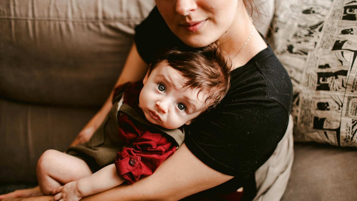 woman in black shirt carrying baby in red dress